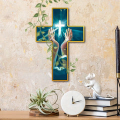 A rustic wooden wall cross featuring a glowing cross and hands raised in prayer.
