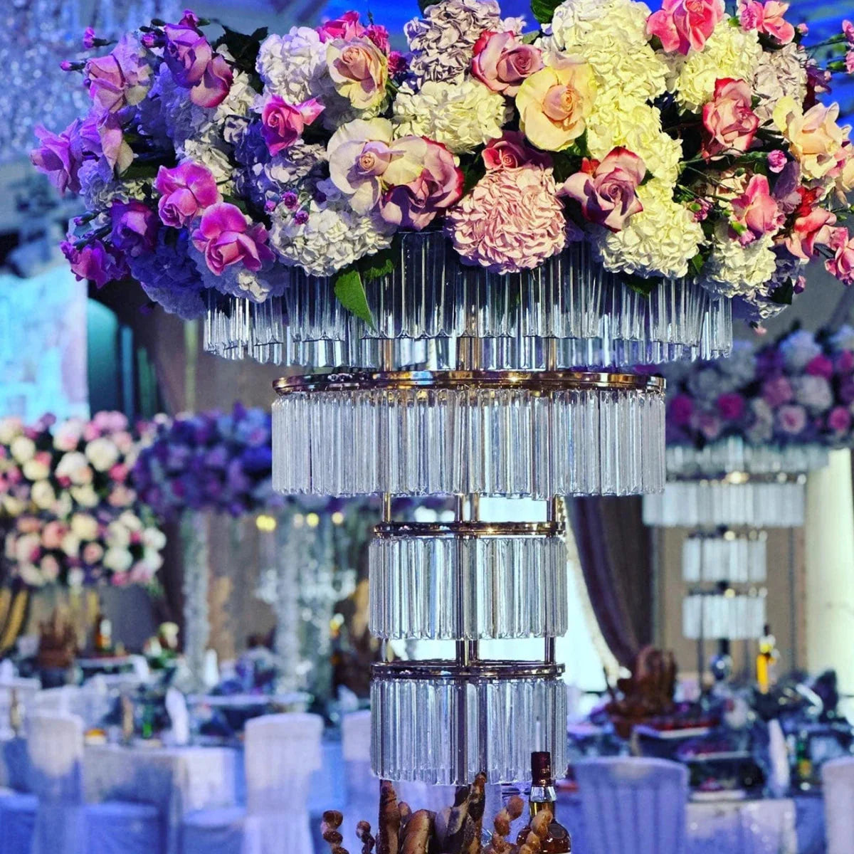 Tall gold crystal wedding centerpiece on a four-layer metal stand, featuring elegant crystal accents and intricate metalwork.