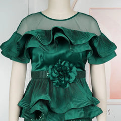 A dark green off-shoulder top with pleated ruffles, a sheer neckline, and a floral waist accent.