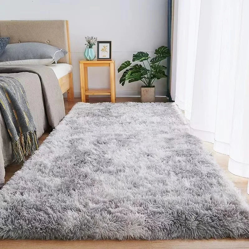 A rectangular gray plush rug with a soft, shaggy texture placed on a bedroom floor.