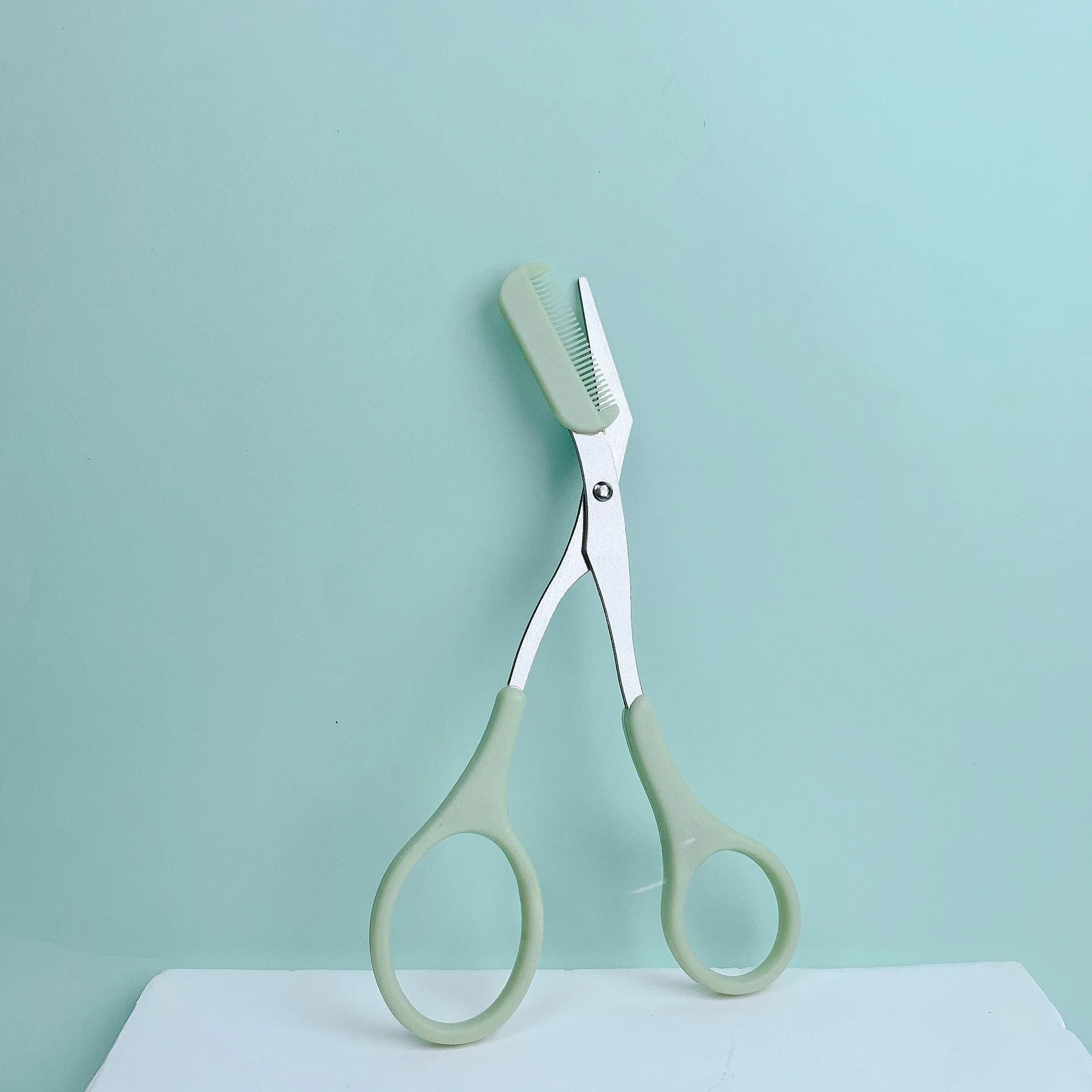 Pink Eyebrow Trimming Scissors with built-in comb, stainless steel grooming tool for precise eyebrow shaping and grooming.