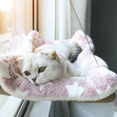A white Scottish Fold cat rests on a plush, star-patterned hanging window hammock.