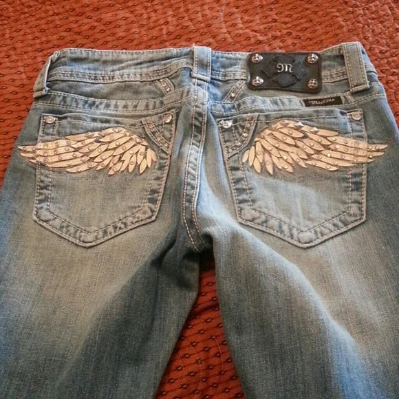 Blue low-rise flared denim jeans with rhinestone wing embroidery and studded pockets, American Vintage Y2K streetwear style.