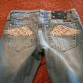 Blue low-rise flared denim jeans with rhinestone wing embroidery and studded pockets, American Vintage Y2K streetwear style.