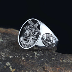 A silver ring featuring an embossed image of Jesus carrying a cross and a sacred heart symbol.