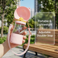 A pink portable pet water bottle with an integrated drinking bowl and an adjustable shoulder strap.
