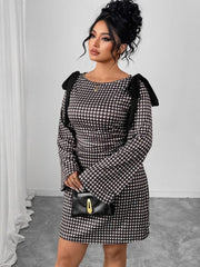 A woman wears a black and white gingham long-sleeve dress with black shoulder tie details.