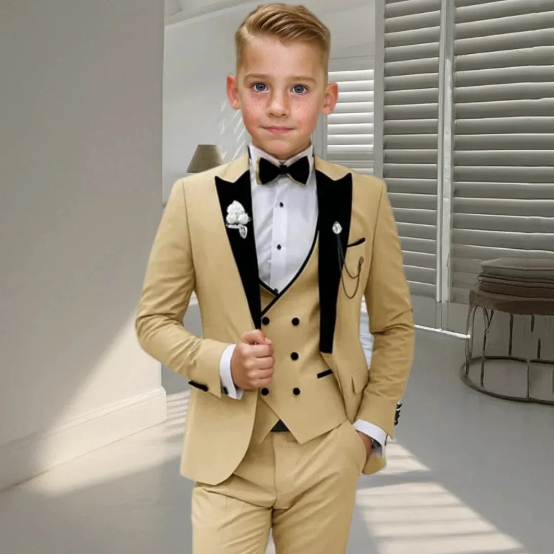 Boy wearing a champagne velvet tuxedo suit set with blazer, shirt, pants, and bow tie, perfect for formal occasions.