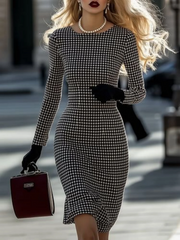 A woman wears a slim-fit, long-sleeve black and white plaid midi dress with a round neckline.