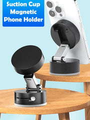 A black magnetic phone holder with a vacuum suction base sits on a wooden table.