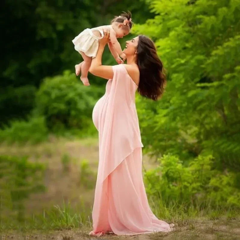 Off-shoulder maternity dress by Showlu Fashion for pregnancy photoshoots, featuring a flowing maxi gown and fluttering shawl.