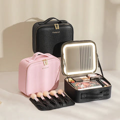 A black and a pink makeup travel case with an integrated LED mirror and brush storage.