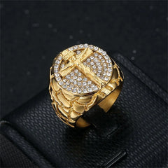 A gold-tone stainless steel ring featuring a crucifix set against a background of clear crystals.