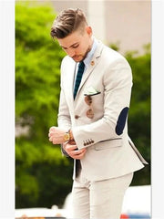 A man wears a beige two-piece suit featuring a single-breasted blazer with dark elbow patches.