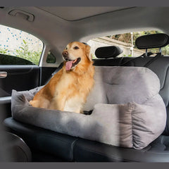 A large, grey suede bolster dog bed sits securely on the backseat of a car with a golden retriever.