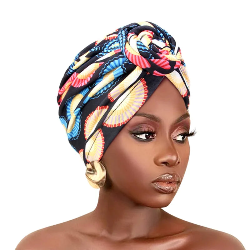 Elegant African print pleated turban with floral design, pre-tied front knot, elastic band, and bandana style headwrap for women.