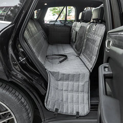 A grey quilted waterproof dog seat cover installed in the back seat of a car.