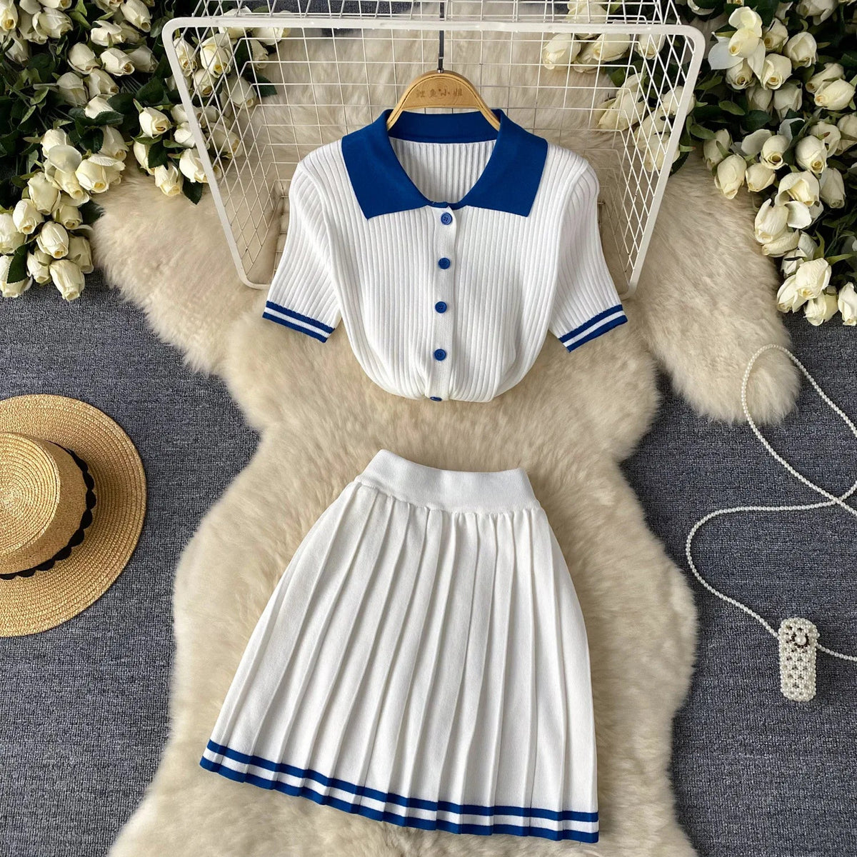 A white two-piece knit set featuring a short-sleeve polo shirt and a pleated mini skirt.