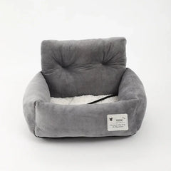 A grey, plush pet car seat with a high backrest and a white, soft interior cushion.