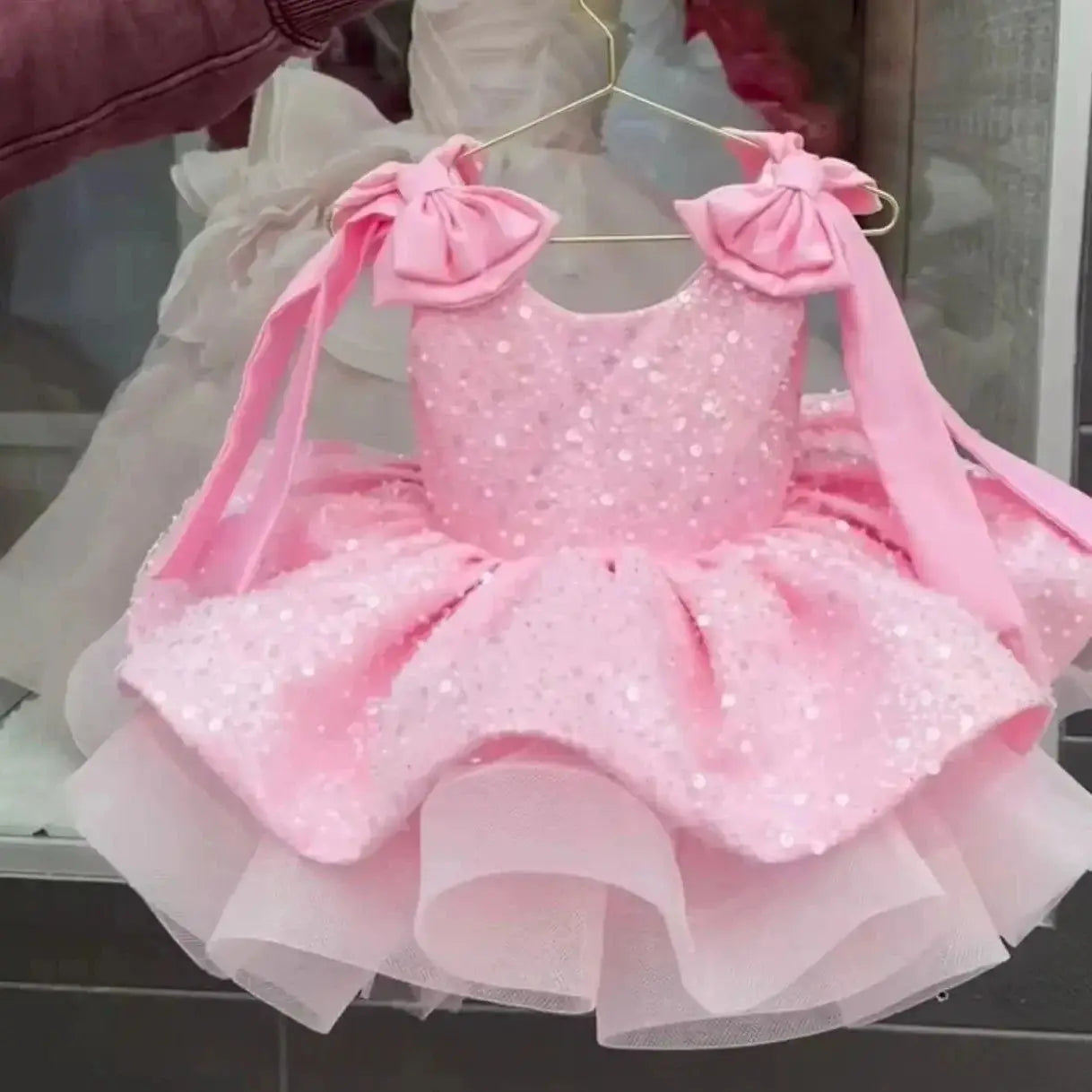 Pink flower girl dress by Showlu Smart General with sleeveless design, bow accents, sequins, and puffy skirt for special occasions.