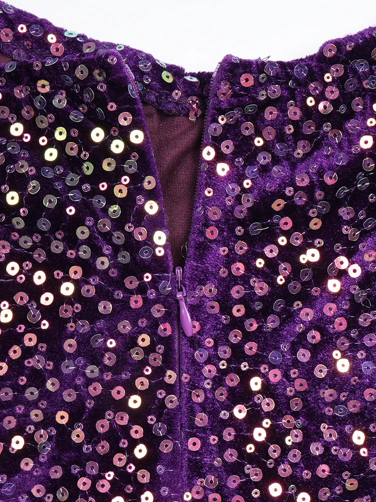 A close-up of a purple velvet dress featuring a zipper closure and all-over sequin embellishment.
