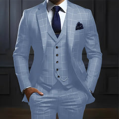 A man wears a light blue three-piece plaid suit with a white shirt and dark blue tie.