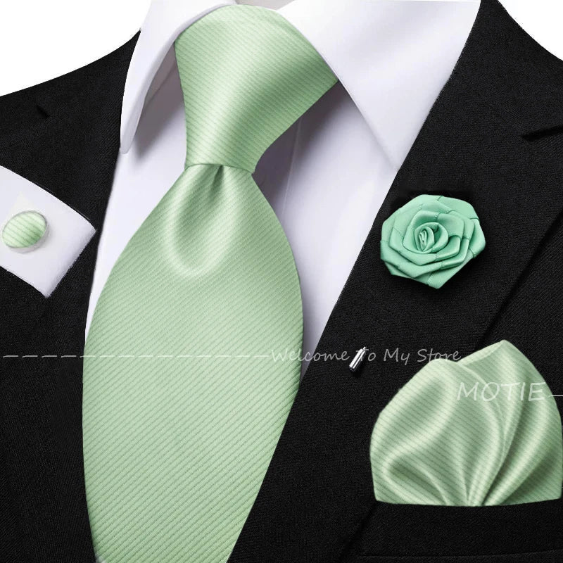 Men's sage green tie set with pocket square, flower brooch, cufflinks, and collar accessory for formal or wedding wear.