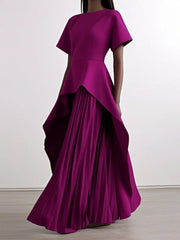 A magenta floor-length dress with short sleeves, a peplum waist, and a pleated irregular hem.