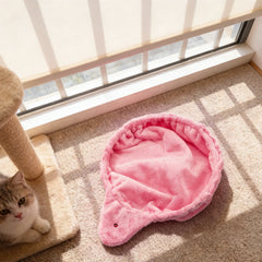 A pink plush cat hammock bed with a small ladybug detail sits on a carpeted floor.
