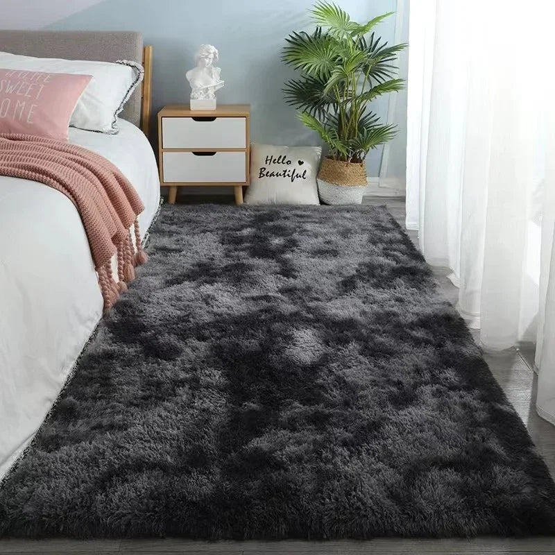 A rectangular, plush gray area rug with a soft, shaggy texture placed in a bedroom.