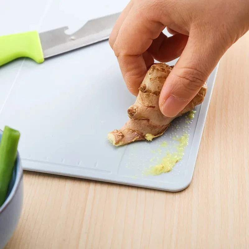 Showlu Smart General collapsible cutting board folded with a knife and vegetables, showcasing its compact, portable kitchen design.