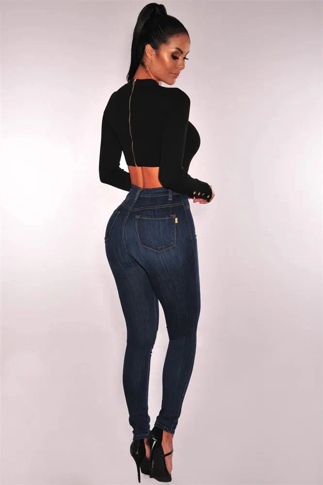 A woman wears high-waisted, dark wash skinny jeans with a slim fit and back pockets.