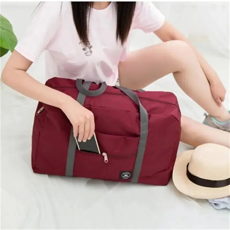 Red, navy, and green multifunctional folding travel bag with single shoulder strap, large capacity, waterproof, used for luggage storage.