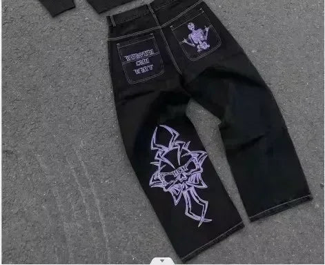Blue low-rise flared denim jeans with rhinestone wing embroidery, studded pockets, and vintage streetwear style.