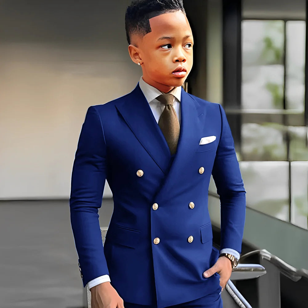 Navy blue solid boy's tuxedo with peak lapel, double-breasted jacket, and matching trousers, suitable for formal events and weddings.