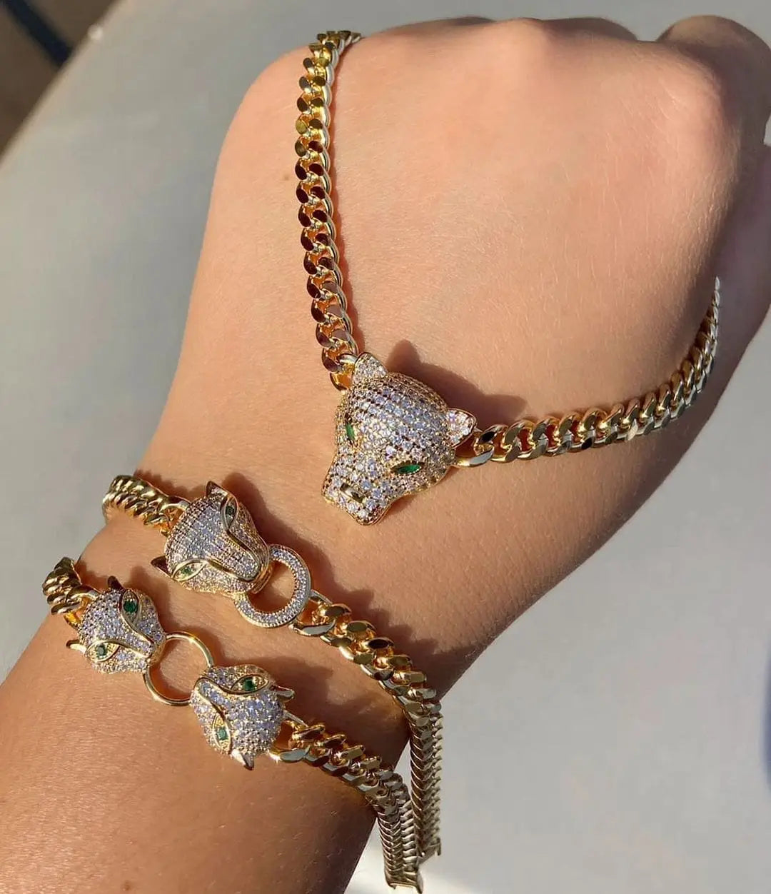 Silver and gold-tone Showlu Store Nation Cuban link bracelet with double jaguar head design and CZ stones, adjustable for women.