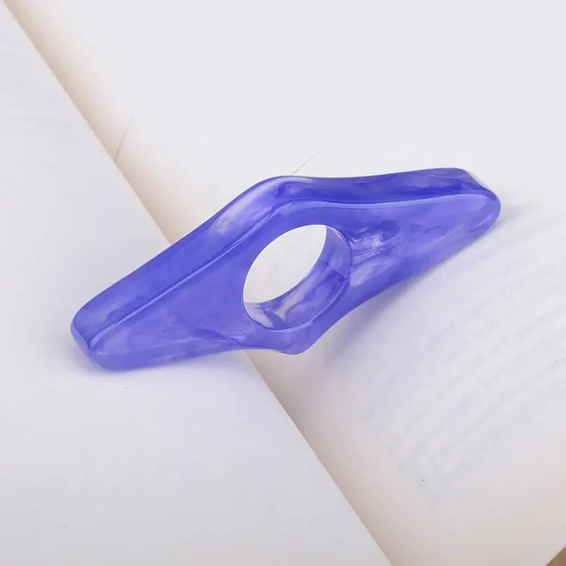 Acrylic thumb book page holder with geometric design, used as a reading support and bookmark for books.