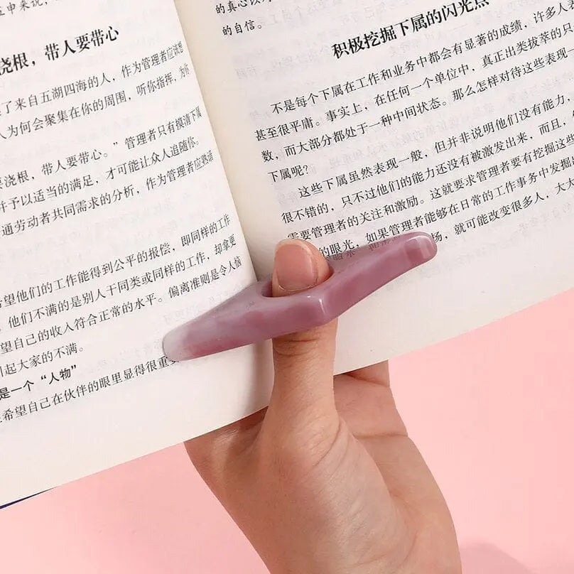 Acrylic thumb book page holder with geometric design for reading support, used as a convenient bookmark and page spreader.