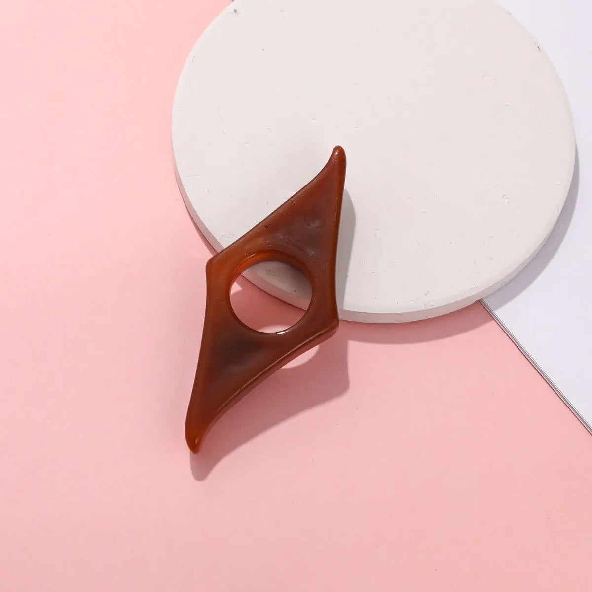 Acrylic thumb book page holder with geometric design, supporting and marking pages during reading or studying.