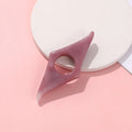 Acrylic thumb book page holder with geometric design, supporting and holding book pages for easy reading.