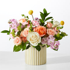 A bouquet of roses, stock, and billy balls in a ribbed ivory ceramic vase.