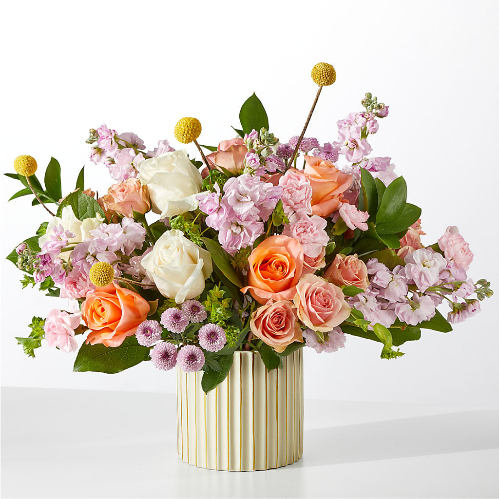 A bouquet of orange, pink, and white flowers in a ribbed ivory vase.