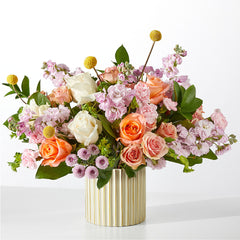 A bouquet of orange, pink, and white flowers in a ribbed ivory vase.