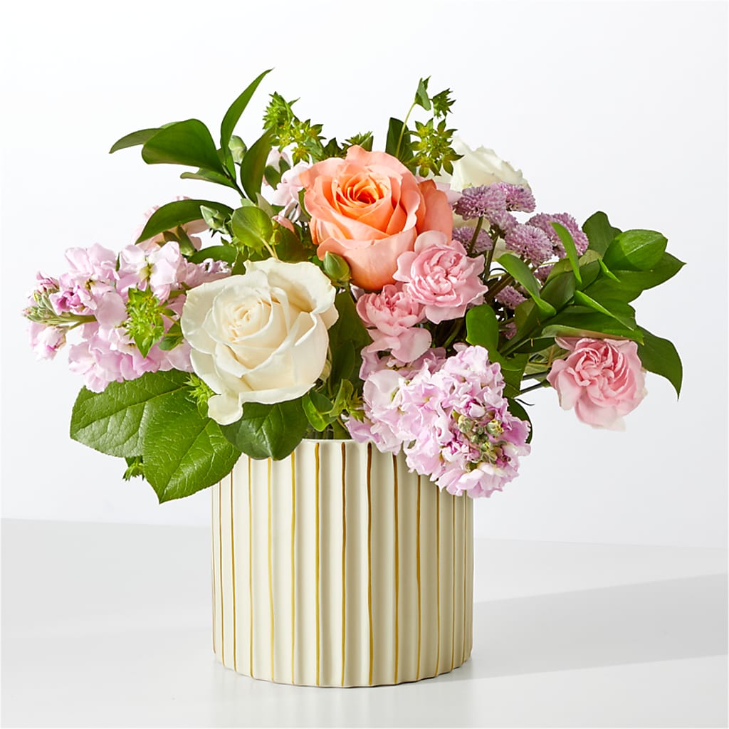 A bouquet of pink and white flowers in a ribbed ivory ceramic vase.