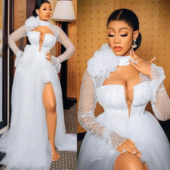 A white tulle wedding dress with a high neck, long sleeves, and a high side slit.