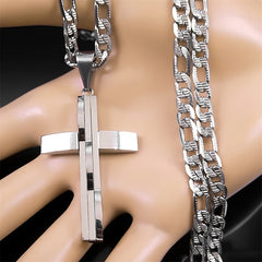 A silver-toned layered cross pendant hangs from a matching curb chain on a mannequin hand.