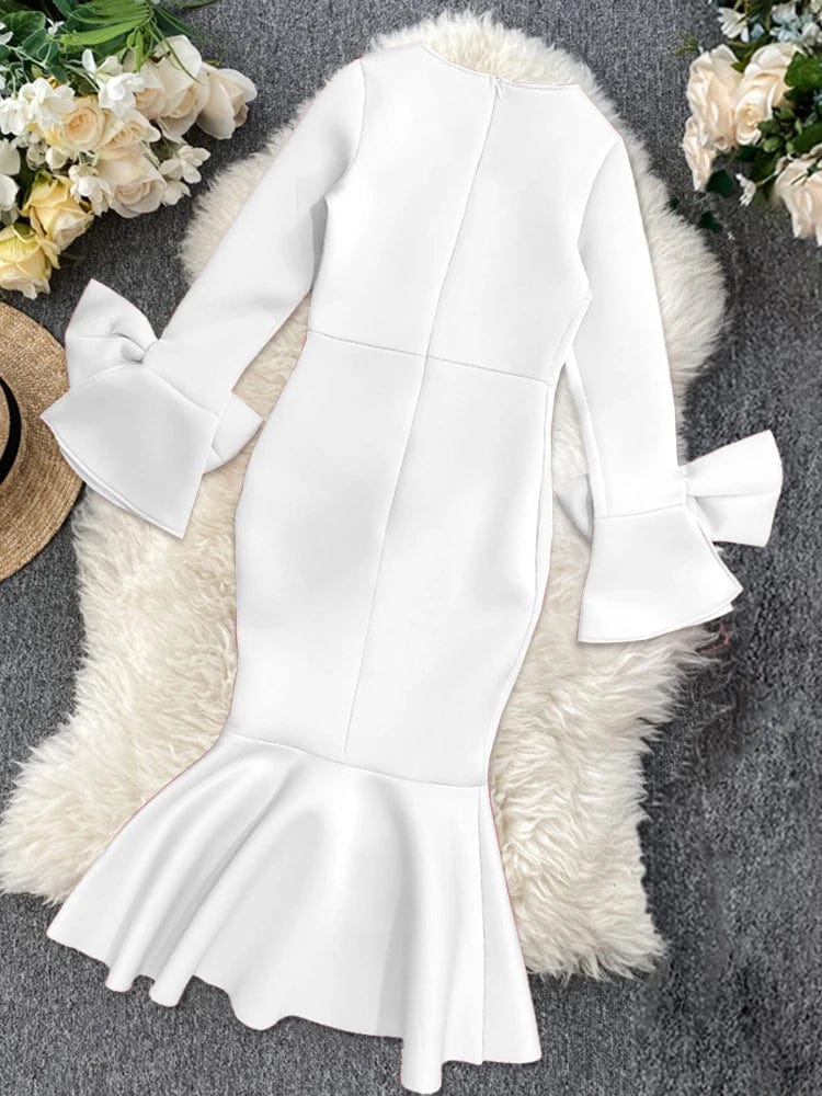A white knee-length bodycon dress with long flare sleeves, bow details, and a ruffled hem.