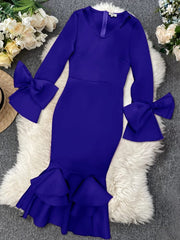 A royal blue bodycon dress with long flared sleeves, bow accents, and a ruffled hem.