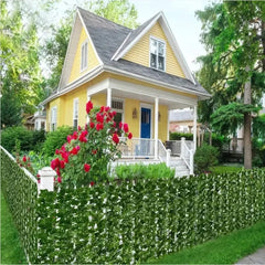 Artificial ivy leaf privacy fence panels installed on a white picket fence in a garden.