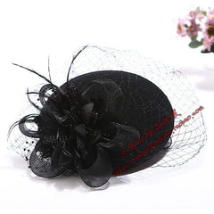 A black vintage fascinator hat featuring a decorative flower, feathers, and a delicate mesh veil.